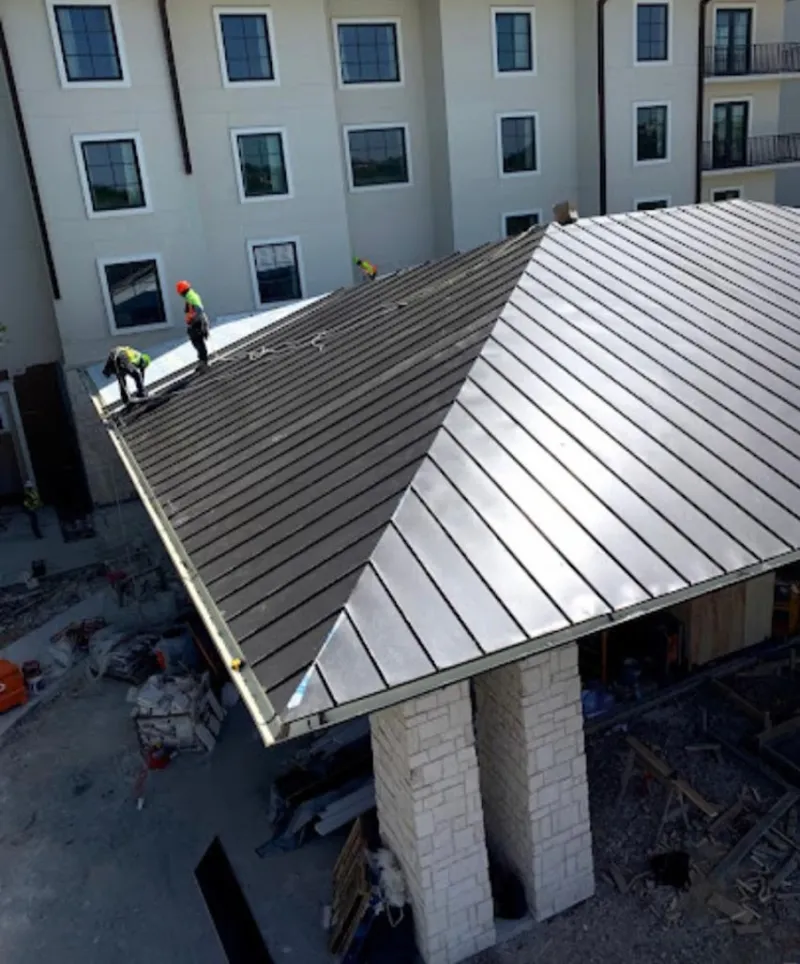 Crew installing standing seam metal roof panels on a commercial project in Enumclaw